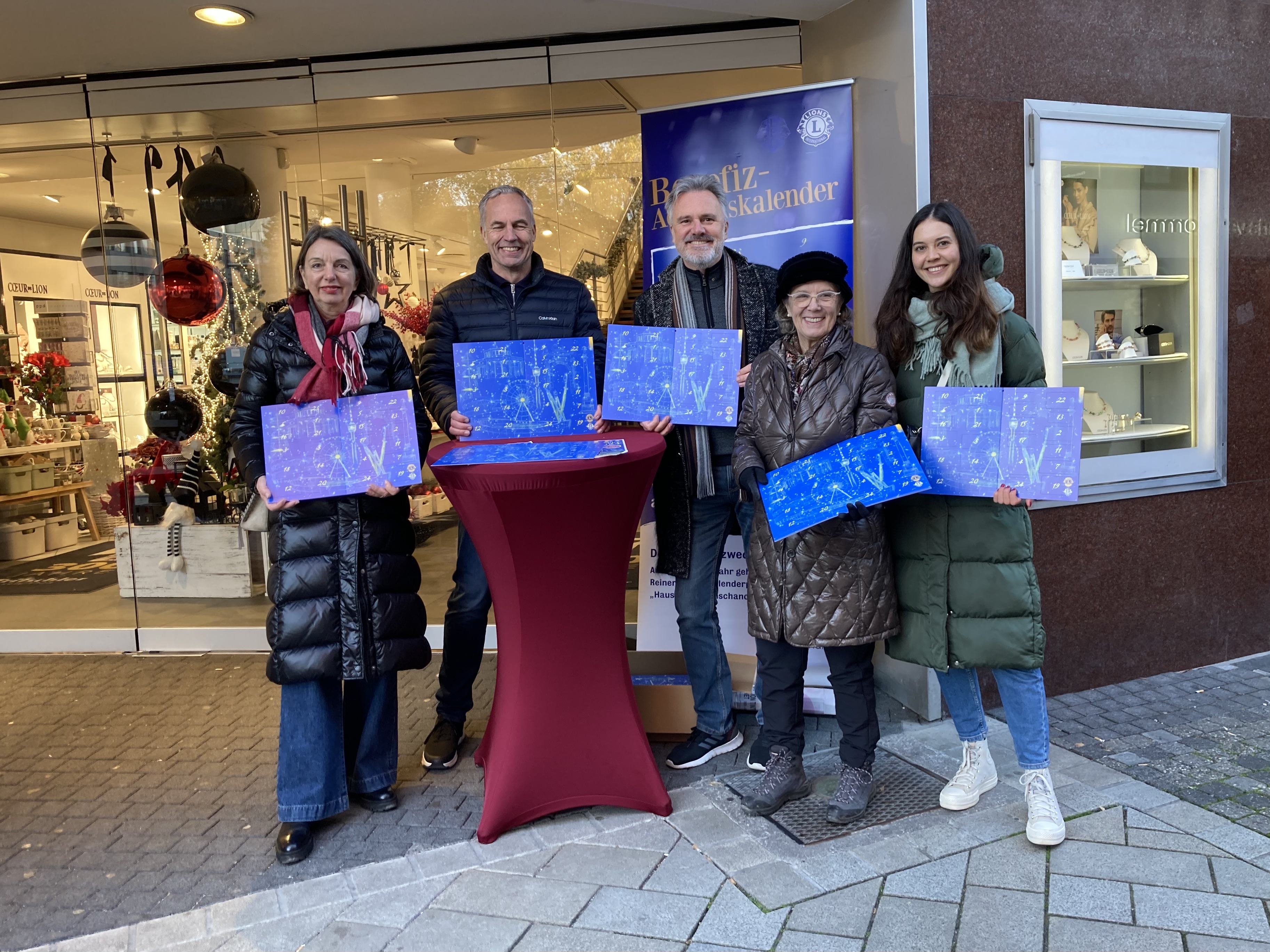 Lions, Leos und freiwillige Helfer verkaufen Benefiz-Adventskalender vor dem Hause Tritschler am Rathausplatz