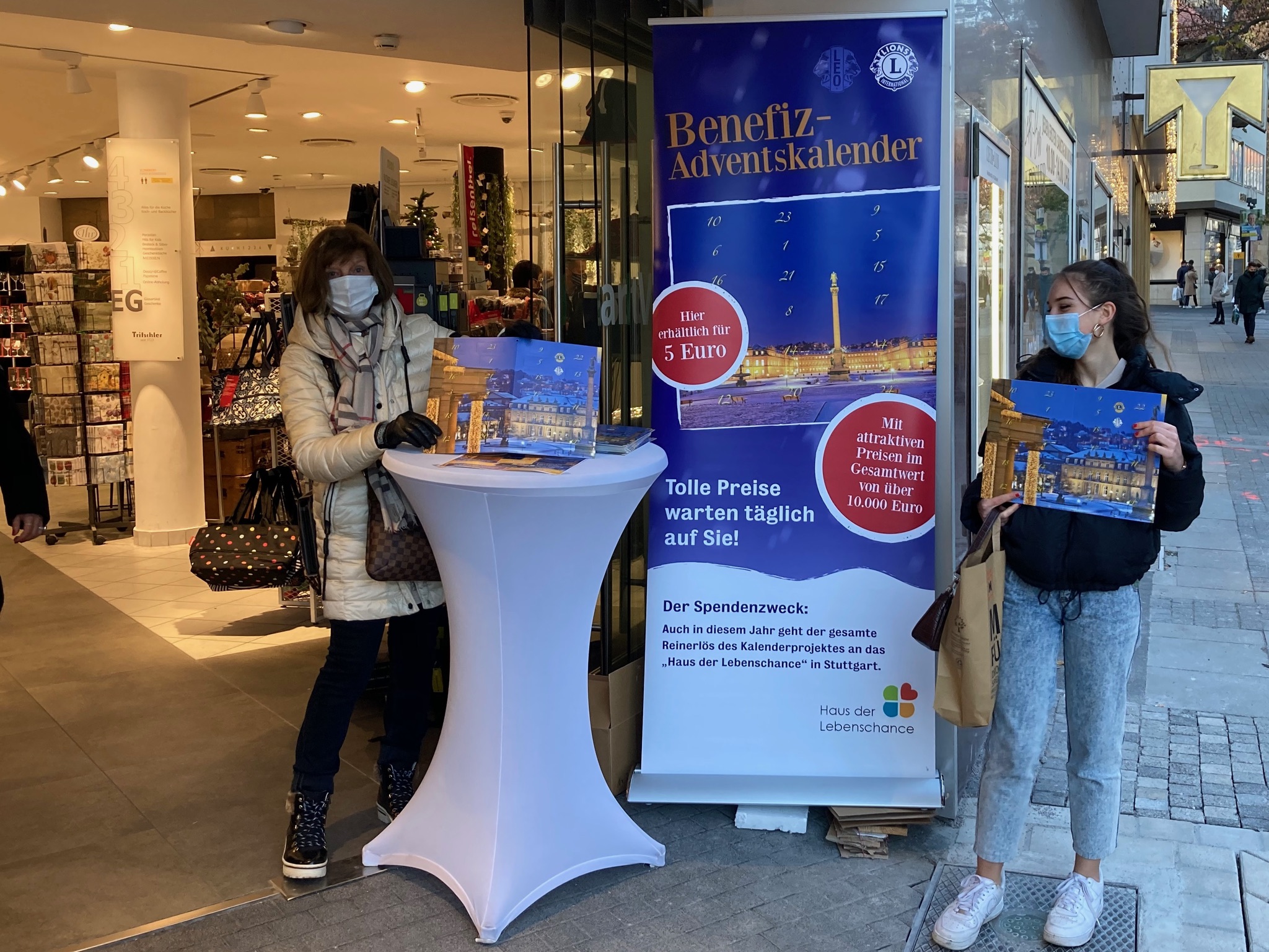 Zwei Frauen verkaufen Benefiz-Adventskalender vor dem Hause Tritschler am Rathausplatz